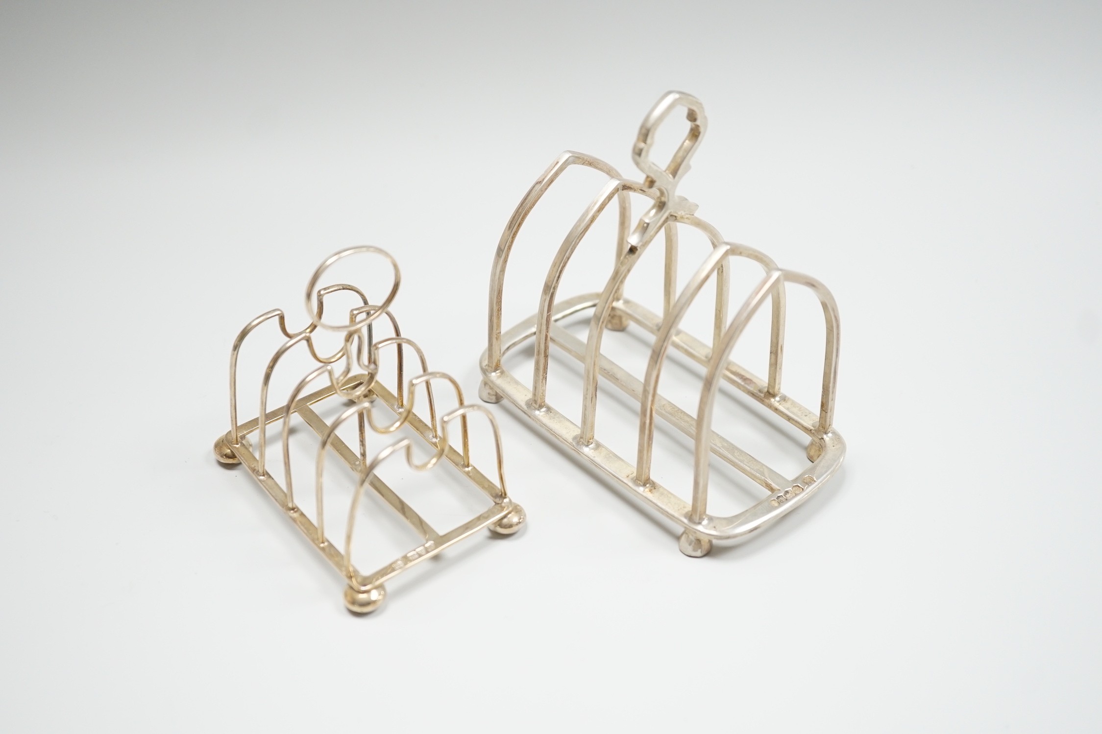 A small Edwardian silver five bar toast rack, Nathan & Hayes, Chester, 1908, 83mm and a later larger silver toast rack, 7.5oz.